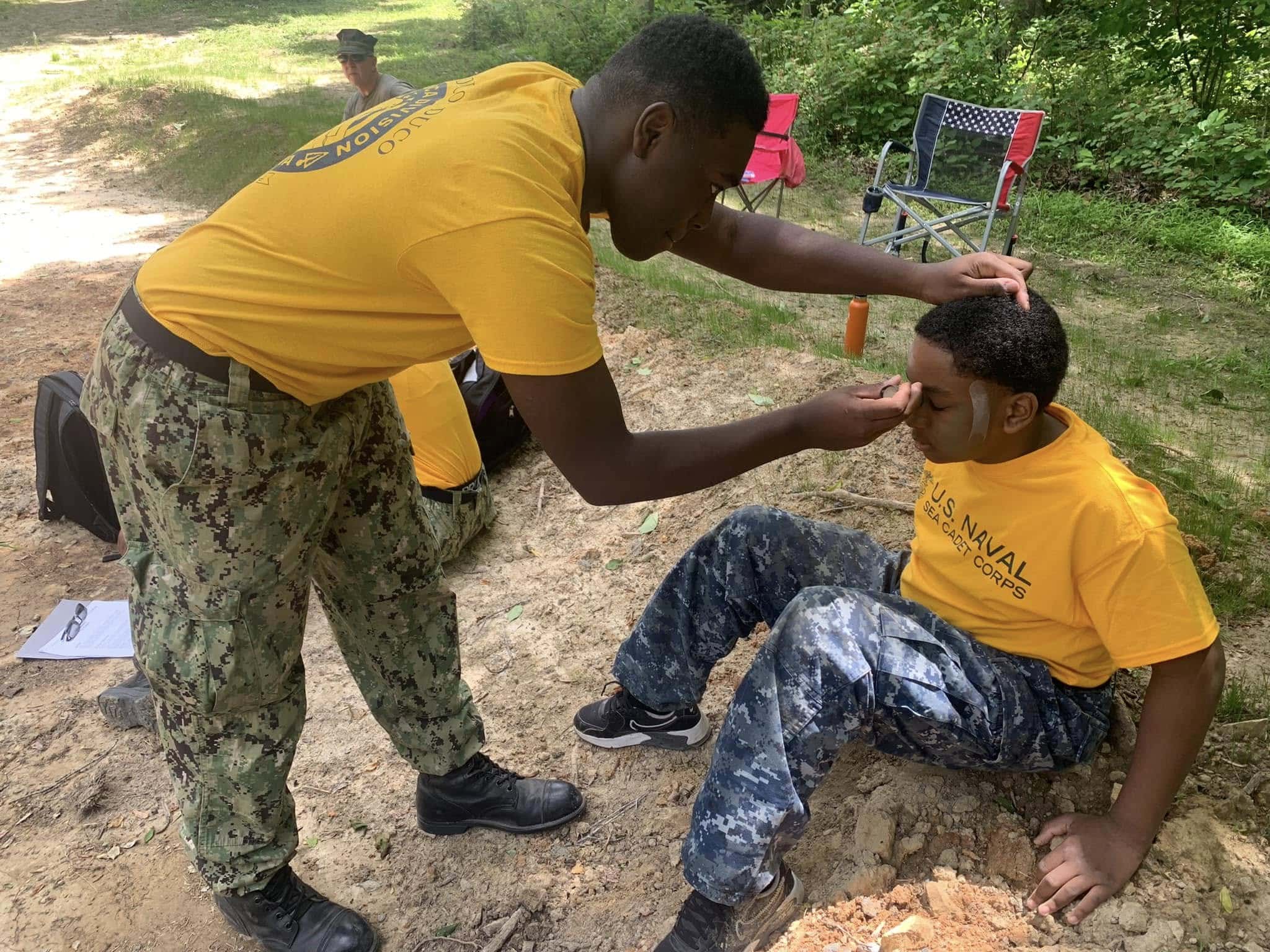 Experienced Sea Cadet mentoring a younger cadet during outdoor training