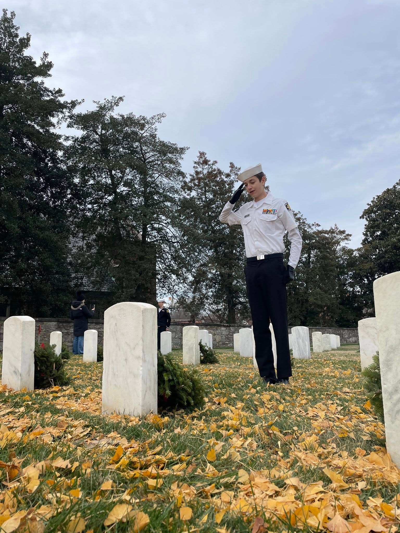 America Division cadet saluting at a fallen veteran's grave during Wreaths Across America at Richmond National Cemetery