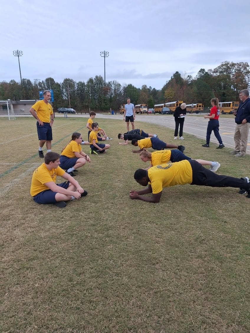 Cadets doing planks on a grass field during outdoor PT