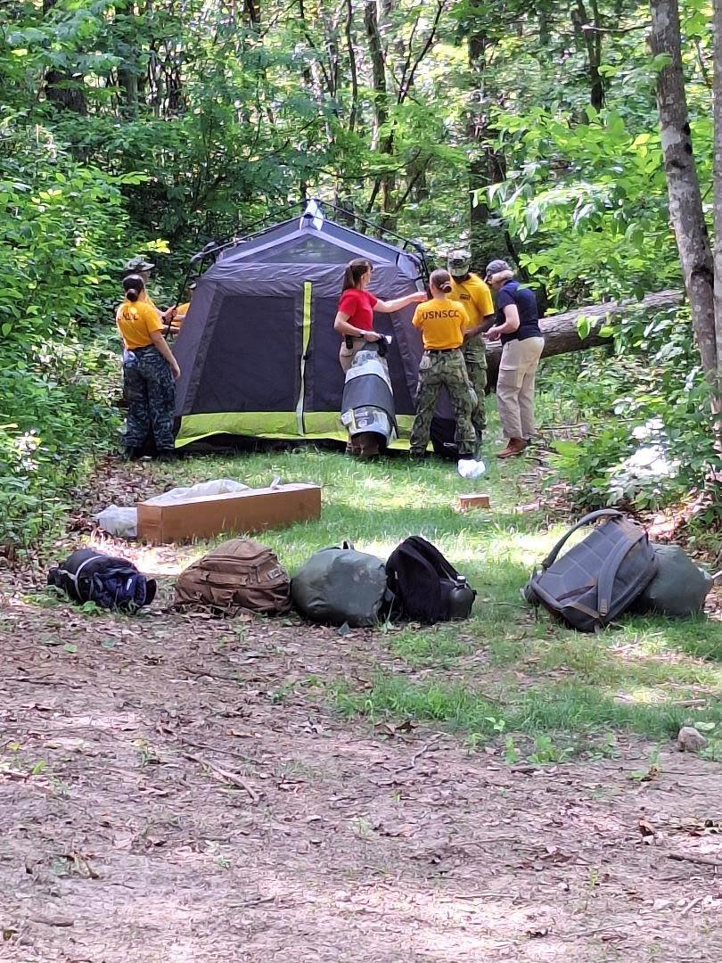 Female cadets setting up a tent in the woods during field training